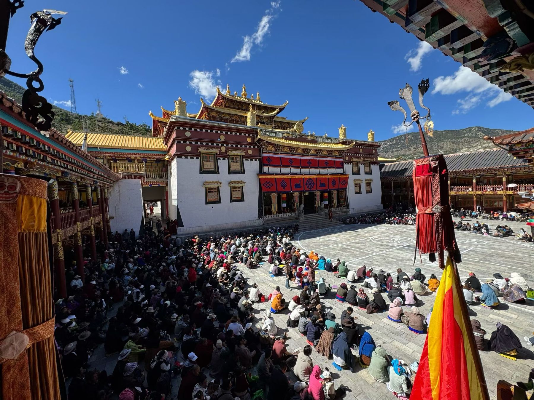 A crowd of Tibetan worshippers seated in the courtyard in front of the main hall