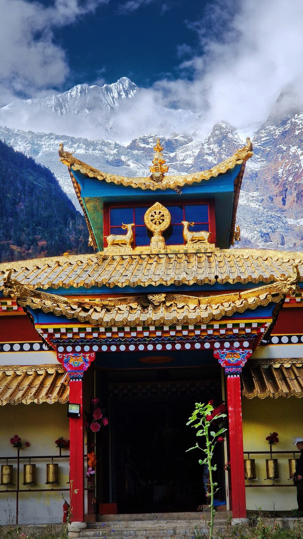 The gilded roof and prayer wheels of a Tibetan temple under glaciers
