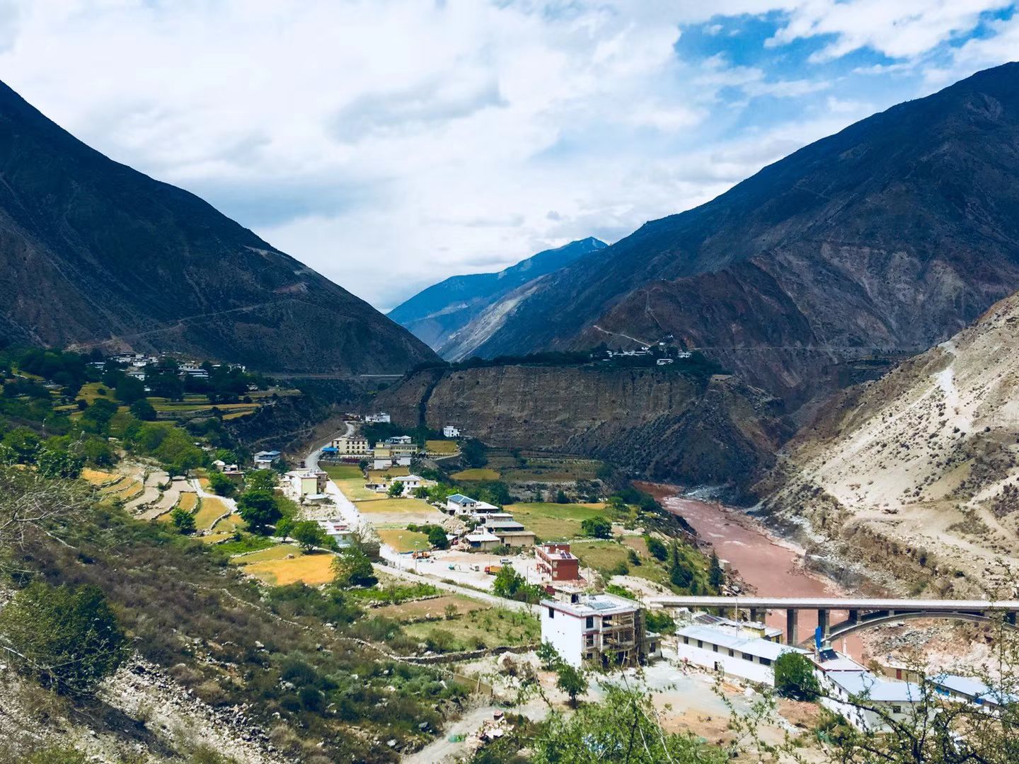 A valley with terraced fields, a village and the brown Mekong river below