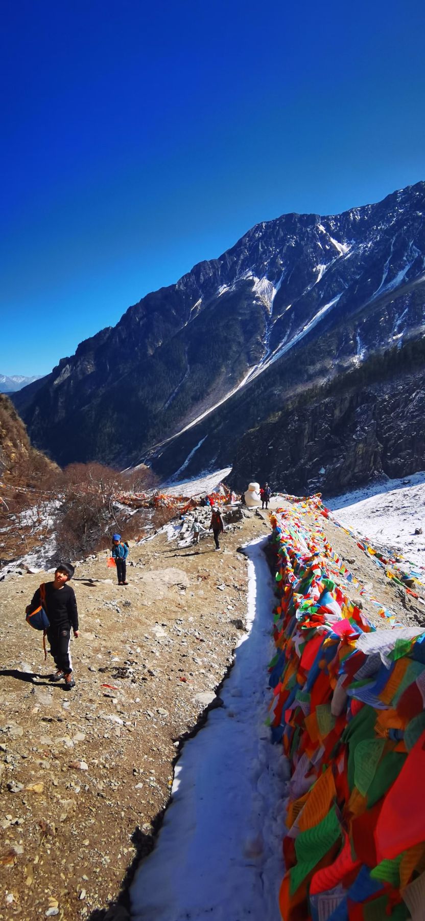 Prayer flags beside a narrow water channel on a mountain trail