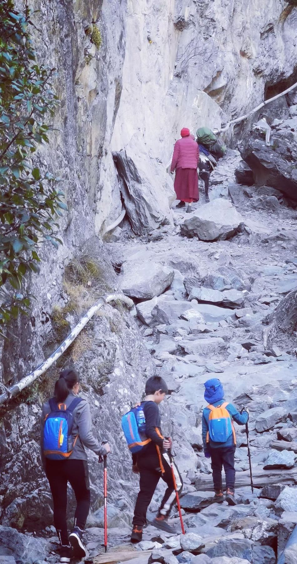 Hikers on a rocky path cut into a pale cliff